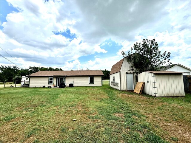 rear view of property with a storage shed and a lawn