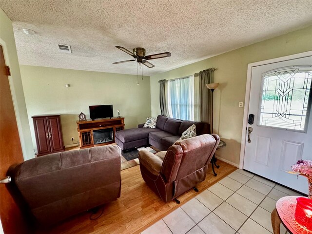 tiled living room with a textured ceiling and ceiling fan