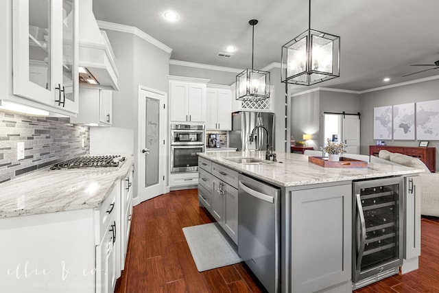 kitchen featuring stainless steel appliances, white cabinets, dark hardwood / wood-style floors, an island with sink, and beverage cooler