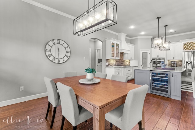 dining room with dark hardwood / wood-style floors, sink, beverage cooler, and ornamental molding