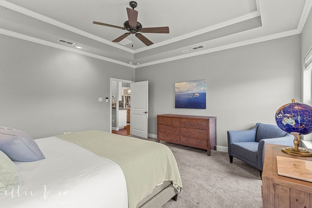 carpeted bedroom with ceiling fan, a tray ceiling, and ornamental molding