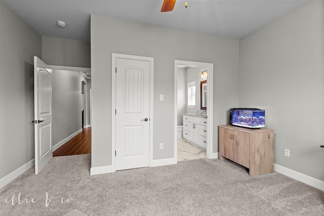 unfurnished bedroom with ensuite bathroom, ceiling fan, and light colored carpet