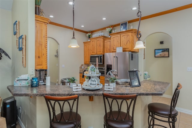 kitchen featuring light tile patterned floors, appliances with stainless steel finishes, pendant lighting, a kitchen bar, and ornamental molding