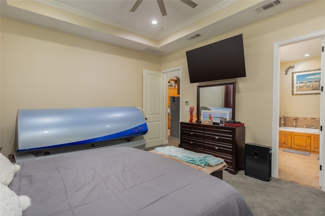 bedroom with a raised ceiling, ensuite bath, light tile patterned floors, and ceiling fan