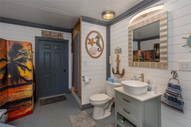 bathroom with wooden walls, toilet, and vanity