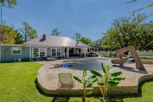 back of house featuring a yard and a playground