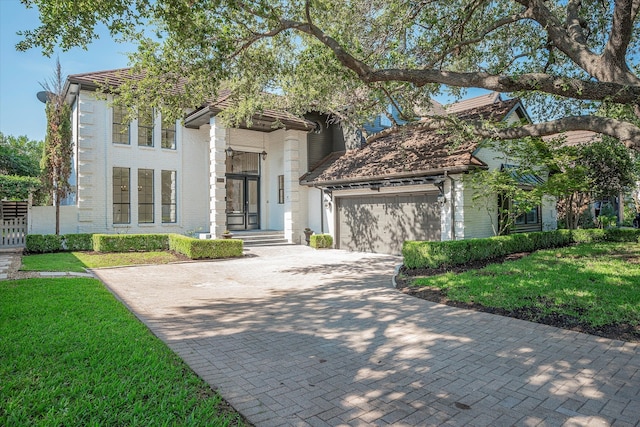 mediterranean / spanish home featuring a garage and a front yard