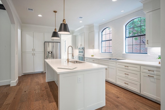 kitchen featuring wood-type flooring, white cabinets, decorative backsplash, an island with sink, and appliances with stainless steel finishes