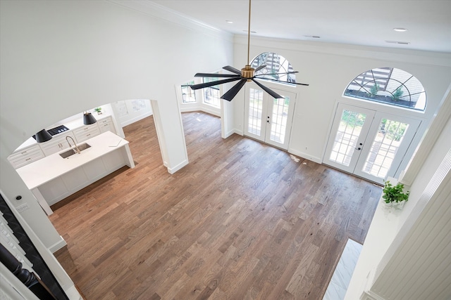 living room with hardwood / wood-style floors, french doors, ceiling fan, ornamental molding, and a towering ceiling