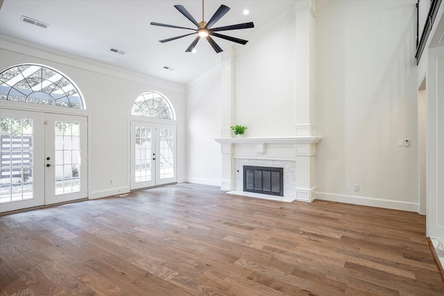 unfurnished living room featuring high vaulted ceiling, french doors, wood-type flooring, and a stone fireplace