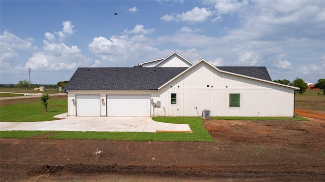 view of front of property with a front yard, central AC unit, and a garage