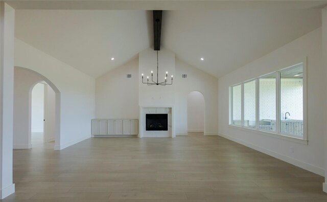 unfurnished living room with high vaulted ceiling, beam ceiling, light hardwood / wood-style flooring, and a notable chandelier