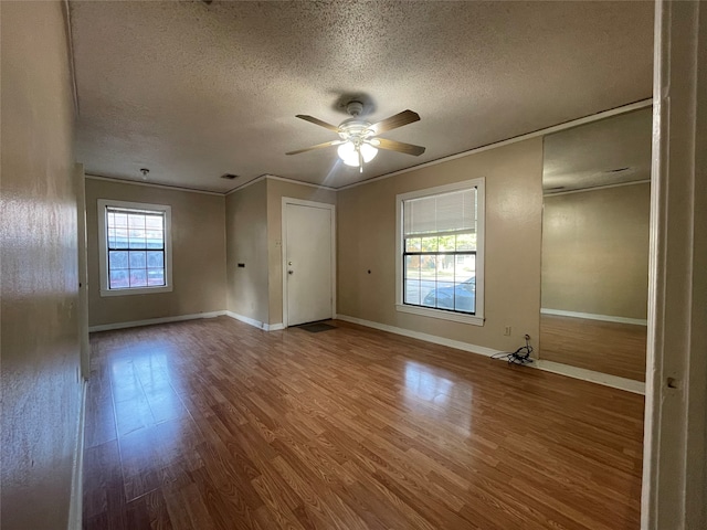 spare room with hardwood / wood-style flooring, a textured ceiling, crown molding, and ceiling fan