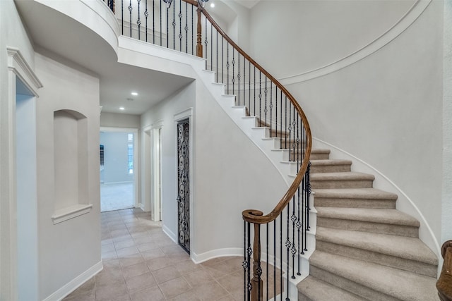 stairs with tile patterned floors and a towering ceiling