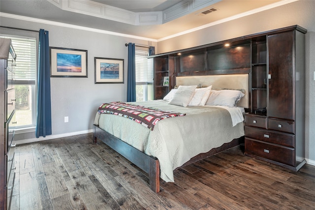 bedroom with dark hardwood / wood-style flooring, a tray ceiling, multiple windows, and ornamental molding