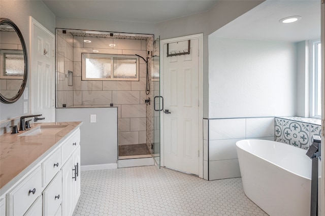 bathroom featuring vanity, independent shower and bath, and tile walls