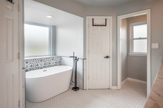 bathroom featuring a healthy amount of sunlight, tile patterned flooring, and a bathing tub