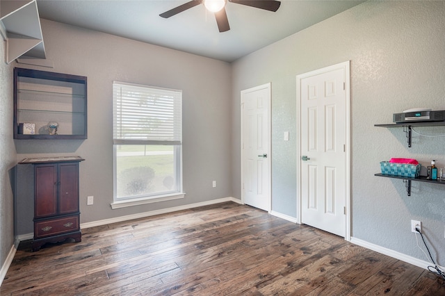 unfurnished bedroom with multiple closets, ceiling fan, and dark hardwood / wood-style flooring