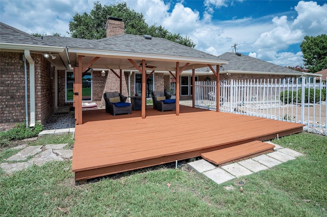 deck with ceiling fan, an outdoor living space, and a lawn