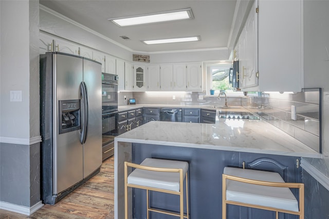 kitchen featuring sink, white cabinetry, a kitchen breakfast bar, kitchen peninsula, and black appliances