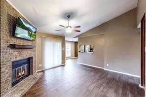 unfurnished living room with ceiling fan, hardwood / wood-style floors, brick wall, vaulted ceiling, and a brick fireplace