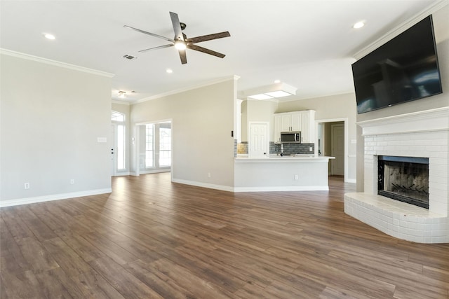 unfurnished living room with a fireplace, hardwood / wood-style flooring, crown molding, and ceiling fan