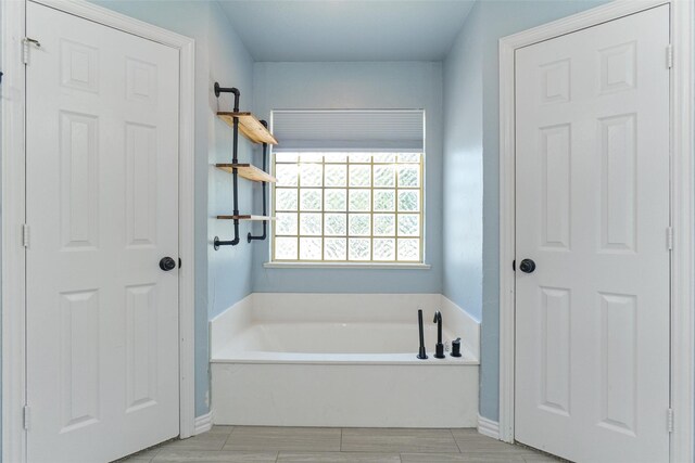 bathroom with a washtub and tile patterned floors