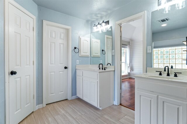 bathroom featuring a textured ceiling, hardwood / wood-style floors, and double vanity