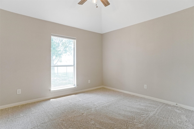 carpeted spare room with plenty of natural light, vaulted ceiling, and ceiling fan