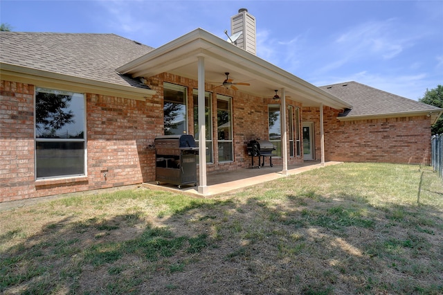 rear view of property with ceiling fan, a patio, and a lawn