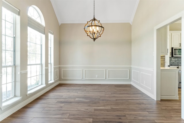 unfurnished dining area featuring a notable chandelier, ornamental molding, and light wood-type flooring