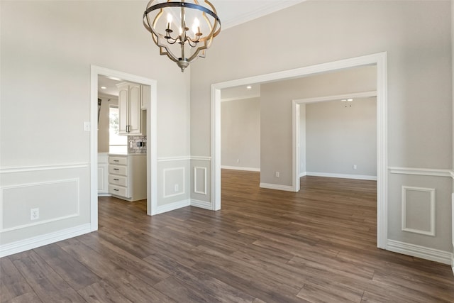 spare room featuring crown molding, dark hardwood / wood-style flooring, and a chandelier