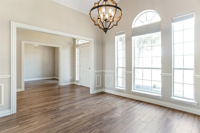 empty room with an inviting chandelier, crown molding, and hardwood / wood-style floors