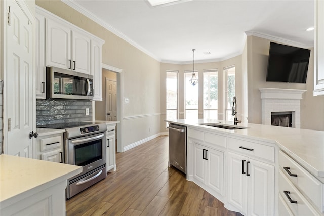 kitchen with stainless steel appliances, decorative backsplash, white cabinetry, a brick fireplace, and dark wood-type flooring