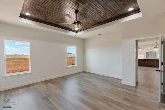 unfurnished room with wooden ceiling, a raised ceiling, and baseboards