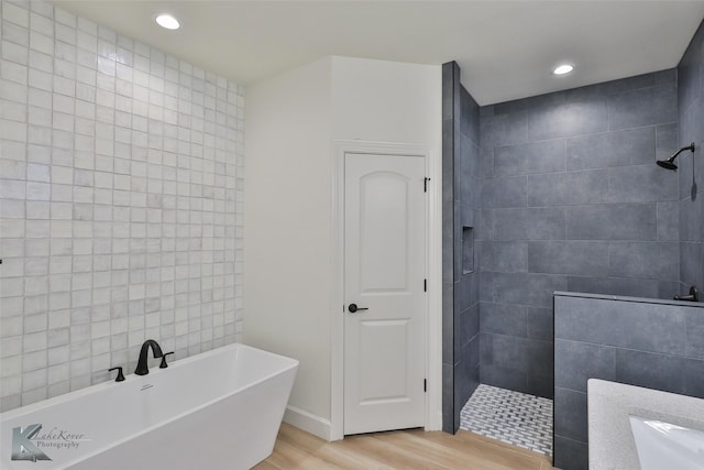 full bathroom featuring a freestanding tub, a walk in shower, wood finished floors, and recessed lighting