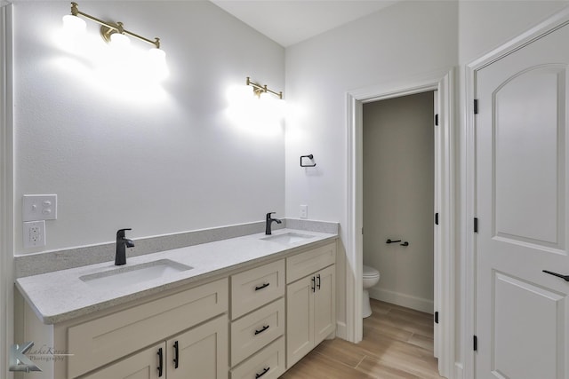 bathroom with wood finished floors, a sink, toilet, and double vanity