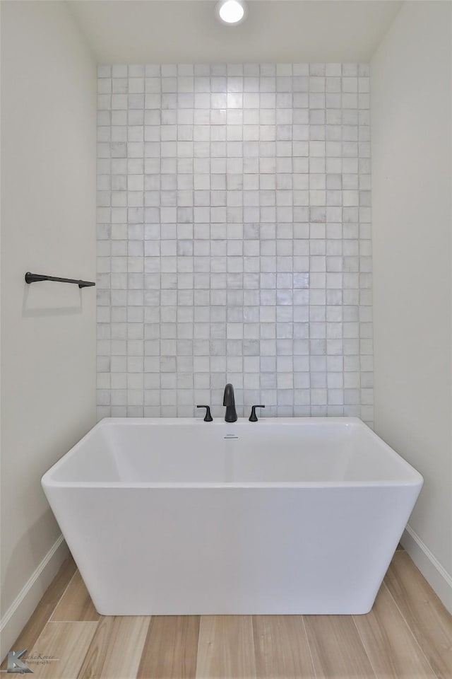 full bathroom featuring baseboards, a soaking tub, tile walls, and wood tiled floor