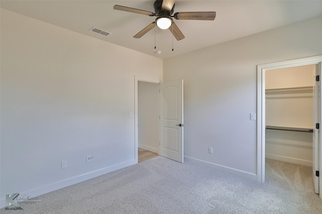 unfurnished bedroom featuring light carpet, baseboards, visible vents, a walk in closet, and a closet