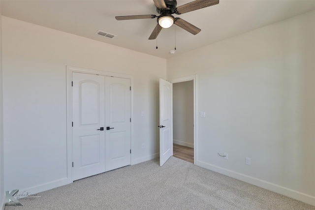 unfurnished bedroom with baseboards, visible vents, light colored carpet, ceiling fan, and a closet