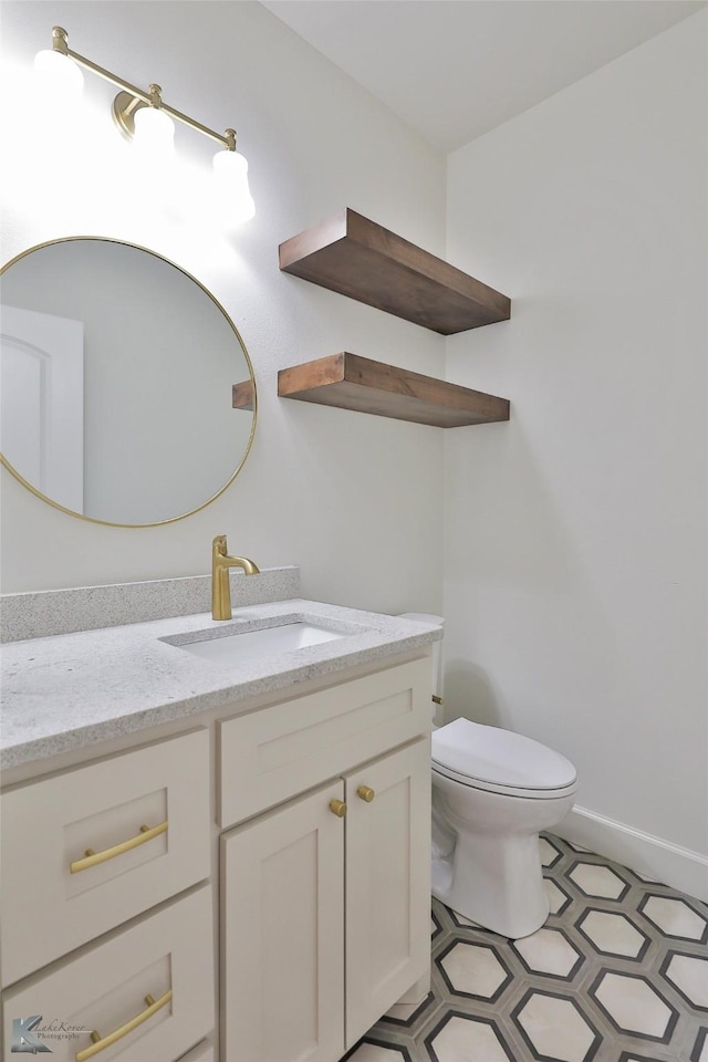 half bath with baseboards, vanity, and toilet