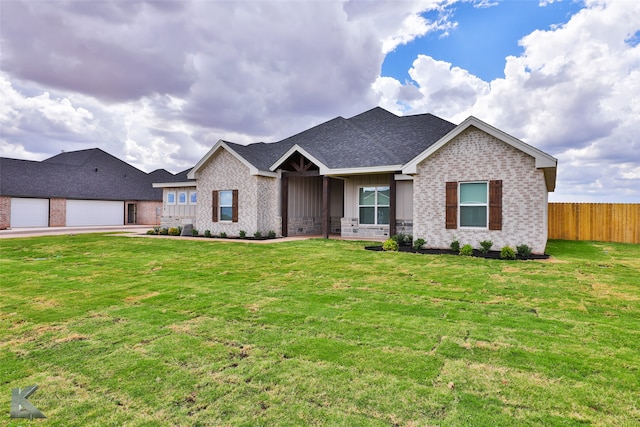 ranch-style house featuring a garage, brick siding, fence, a front lawn, and board and batten siding