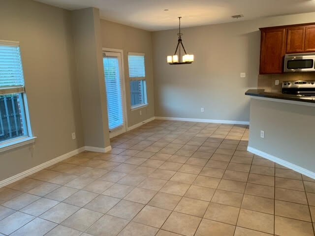 kitchen featuring a chandelier, light tile patterned floors, pendant lighting, and appliances with stainless steel finishes