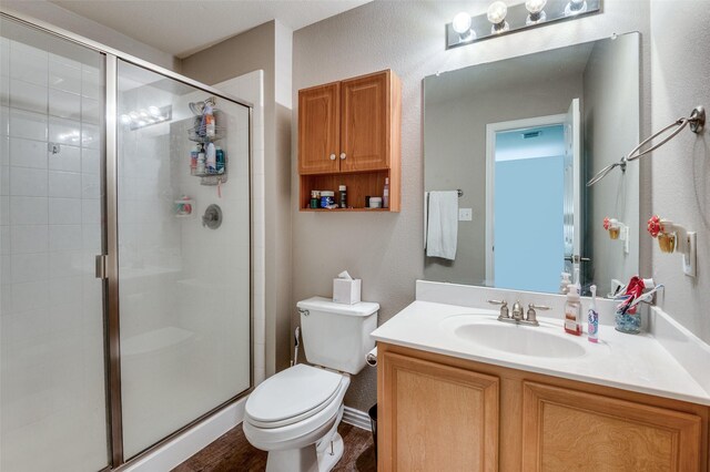 bathroom with a shower with door, vanity, hardwood / wood-style flooring, and toilet