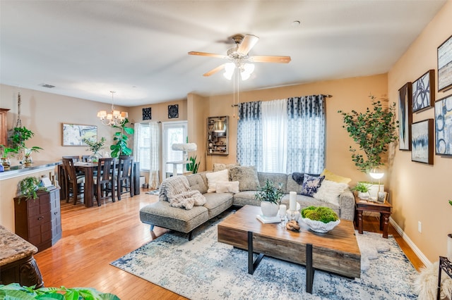 living room with ceiling fan with notable chandelier and light wood-type flooring