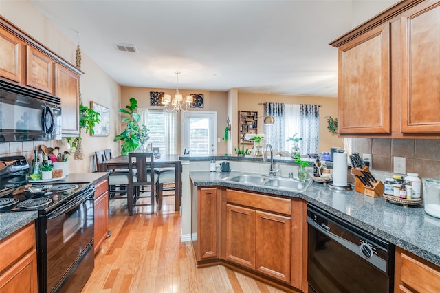 kitchen with tasteful backsplash, kitchen peninsula, light hardwood / wood-style floors, black appliances, and sink