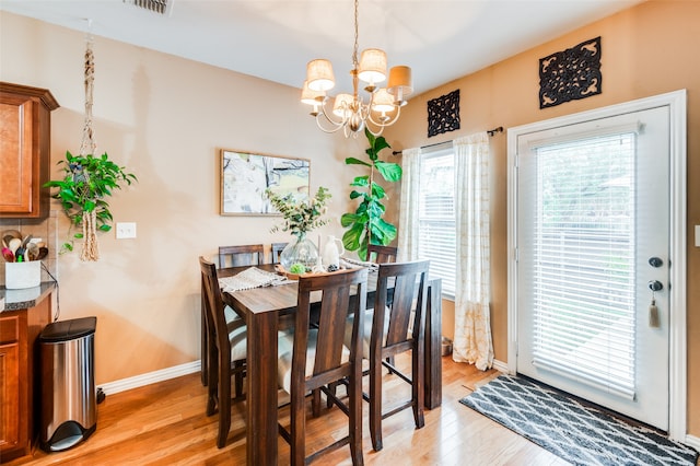 dining room with light hardwood / wood-style floors and an inviting chandelier