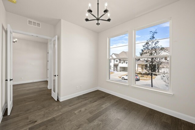 unfurnished dining area with a notable chandelier and dark wood-type flooring