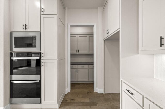 kitchen with built in microwave, stainless steel double oven, white cabinetry, and dark hardwood / wood-style flooring