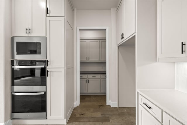 kitchen featuring double oven, white cabinetry, dark hardwood / wood-style floors, and built in microwave